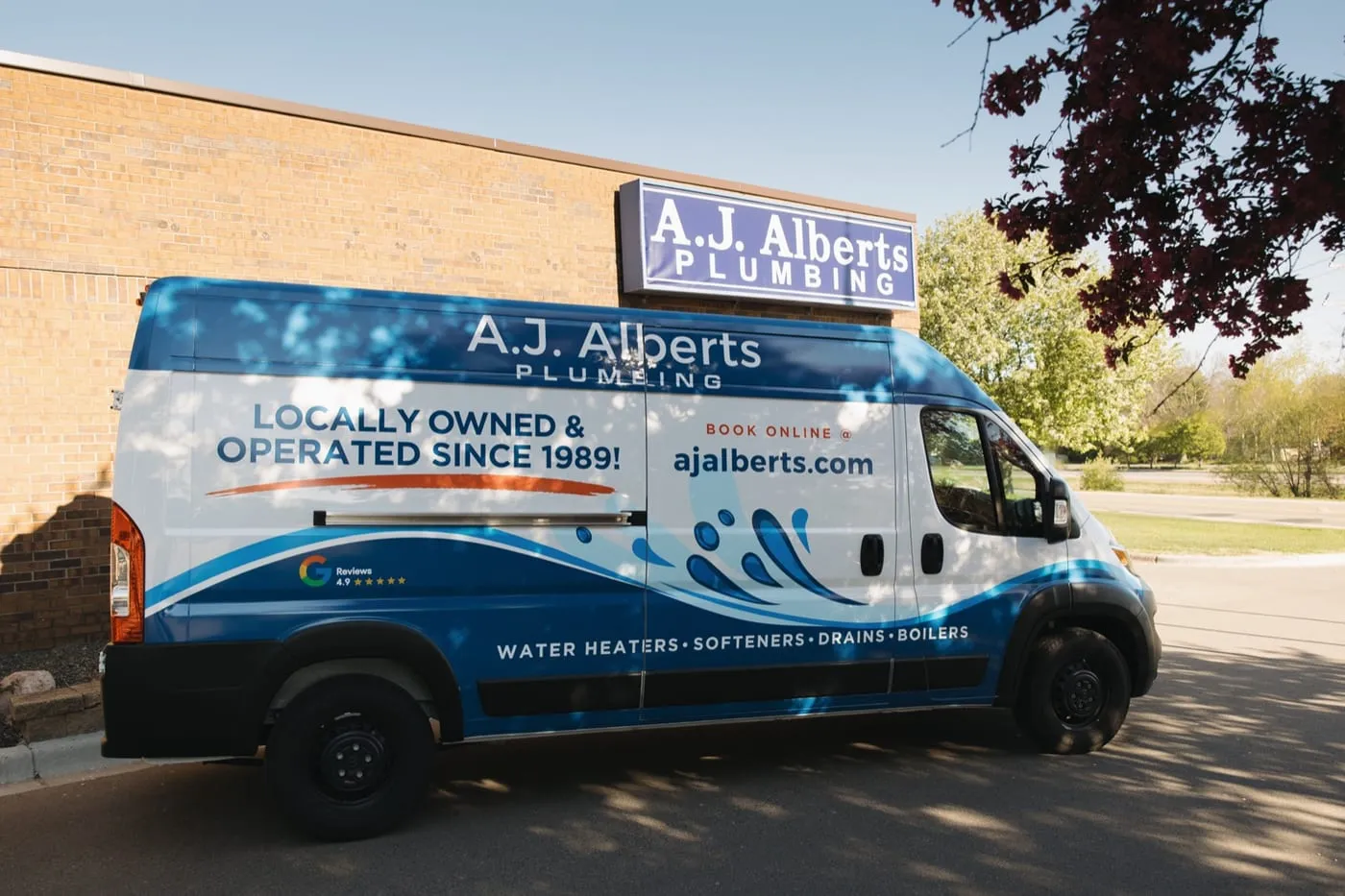 A.J. Alberts Plumbing service van parked outside the Woodbury showroom on Afton Road, locally owned and operated since 1989