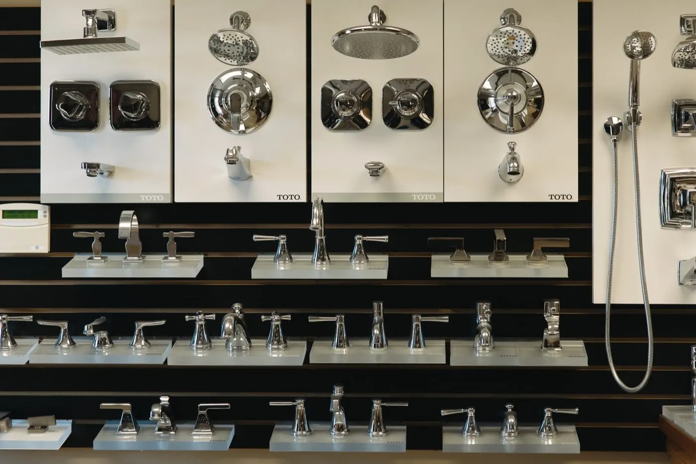 A.J. Alberts Plumbing showroom interior wall in Woodbury, Minnesota, featuring working displays of TOTO and Kohler faucets, fixtures, and shower systems